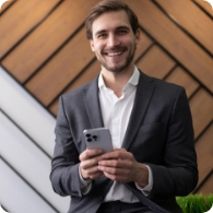 Homem de terno usando o celular e sorrindo